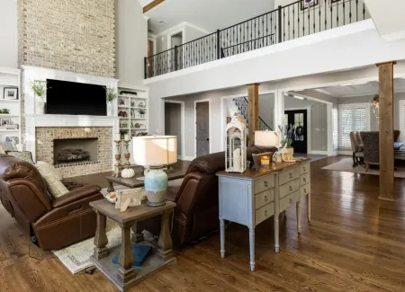 Living room luxury with custom loft railing and wood beam design.